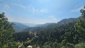 Paesaggio montuoso con edifici sparsi e fitta foresta.