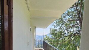 Un balcone con pavimento in piastrelle scure, pareti bianche e ringhiera in metallo.