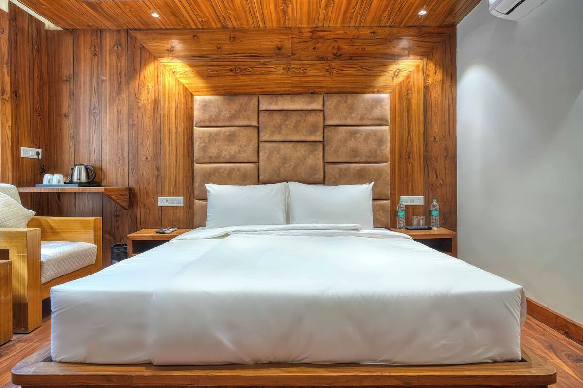 A neatly made bed with a wooden headboard, a bedside table with a lamp, and a chair.