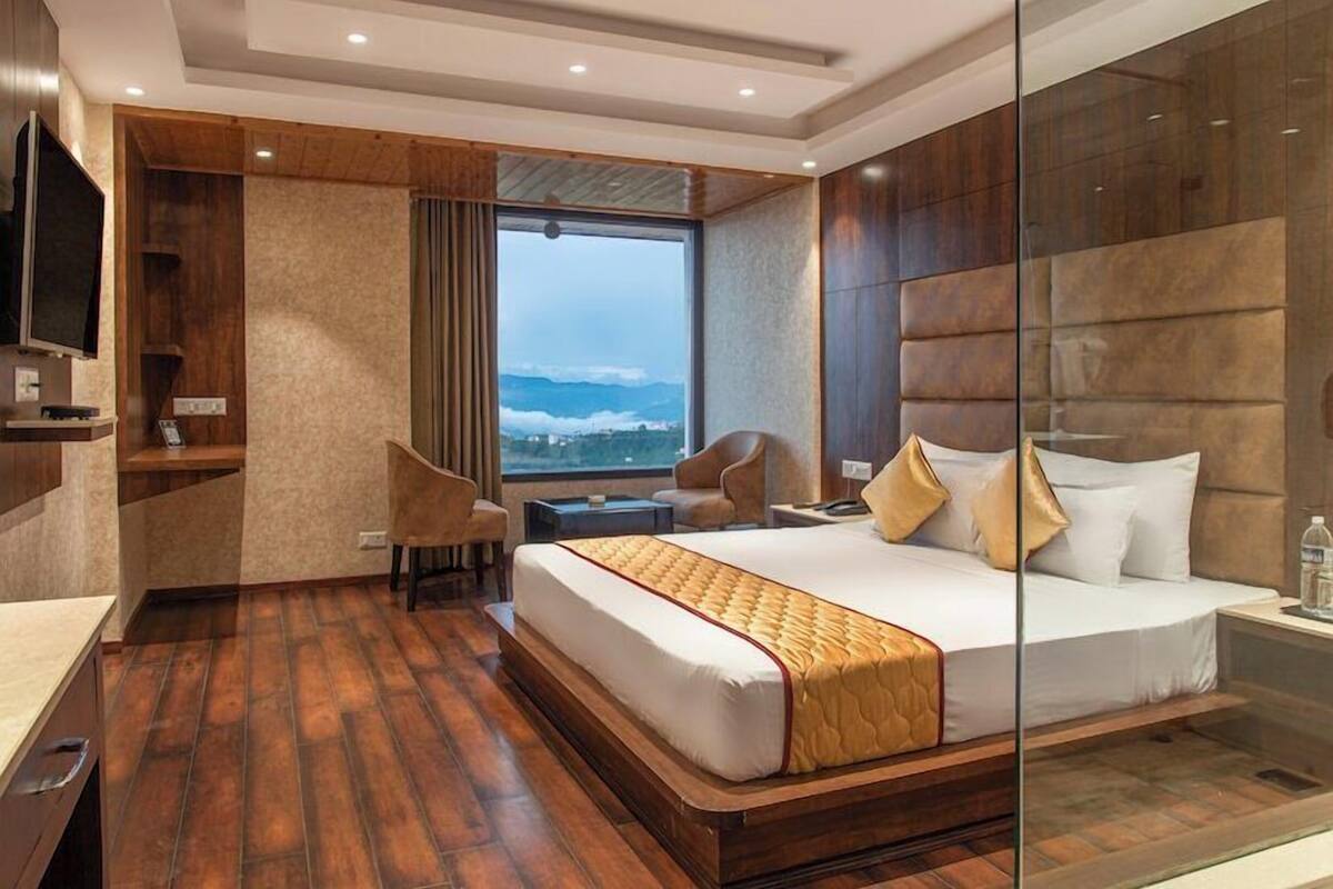 A modern hotel room with a large bed, a desk, a chair, and a television.