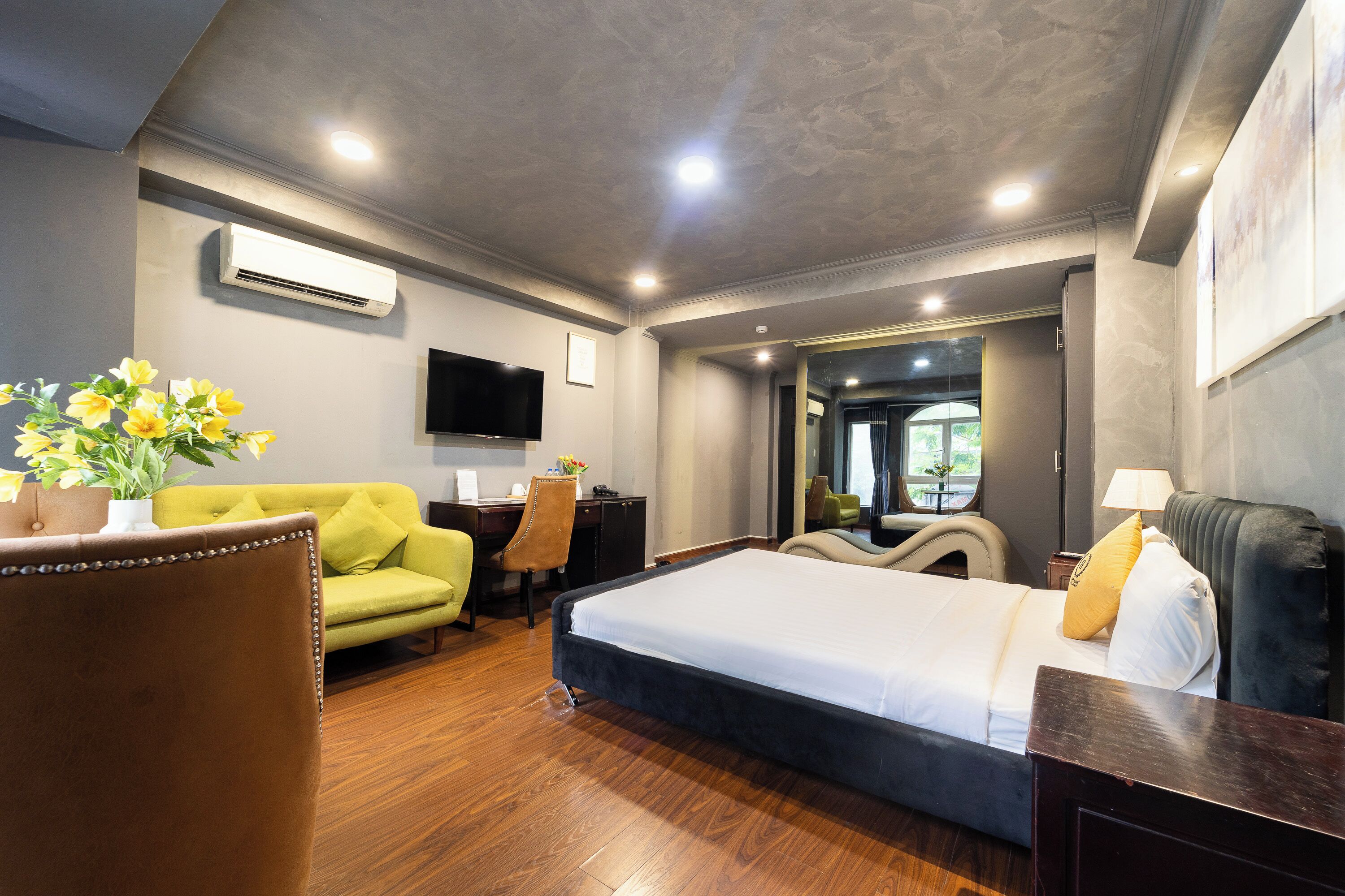 A hotel room with a bed, a desk, a sofa, and a TV.
