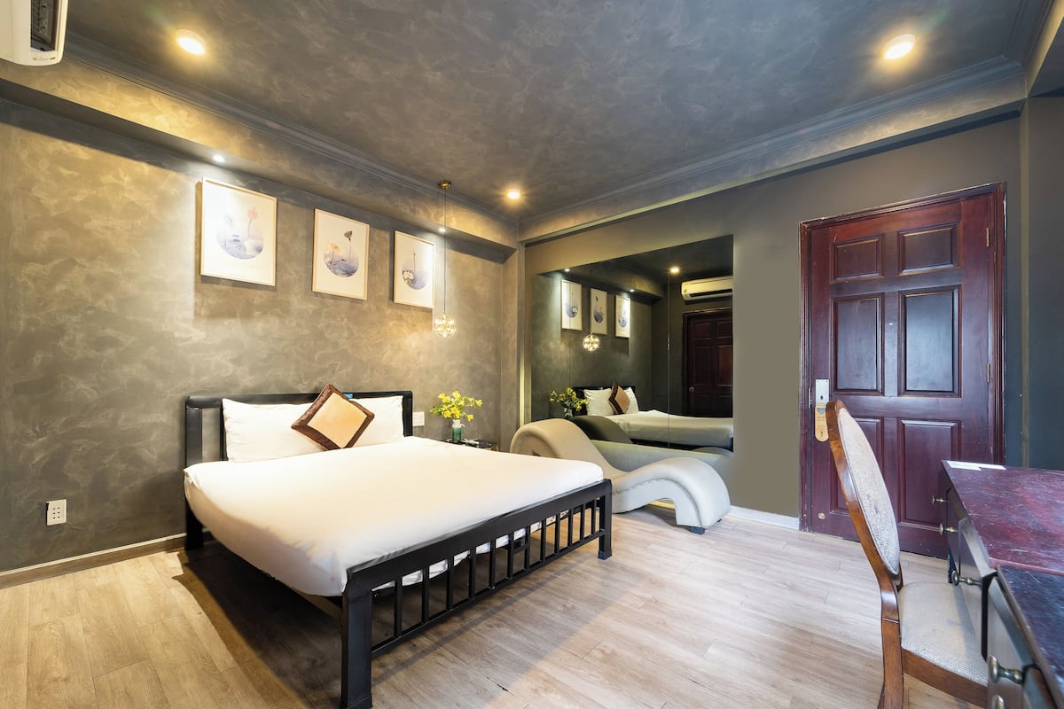 A bedroom with a bed, a chair, a desk, and a door.