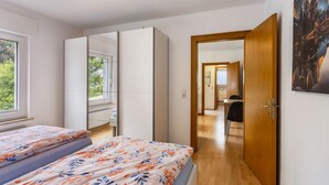 A bedroom with a bed, a wardrobe, a desk, and a door leading to a bathroom. - Apartment 'Rumphorst' with Shared Terrace, Private Garden and Wi-Fi (Kirchhundem)