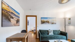 A modern living room with a wooden dining table, a green sofa, and a white coffee table. - Apartment 'Rumphorst' with Shared Terrace, Private Garden and Wi-Fi (Kirchhundem)