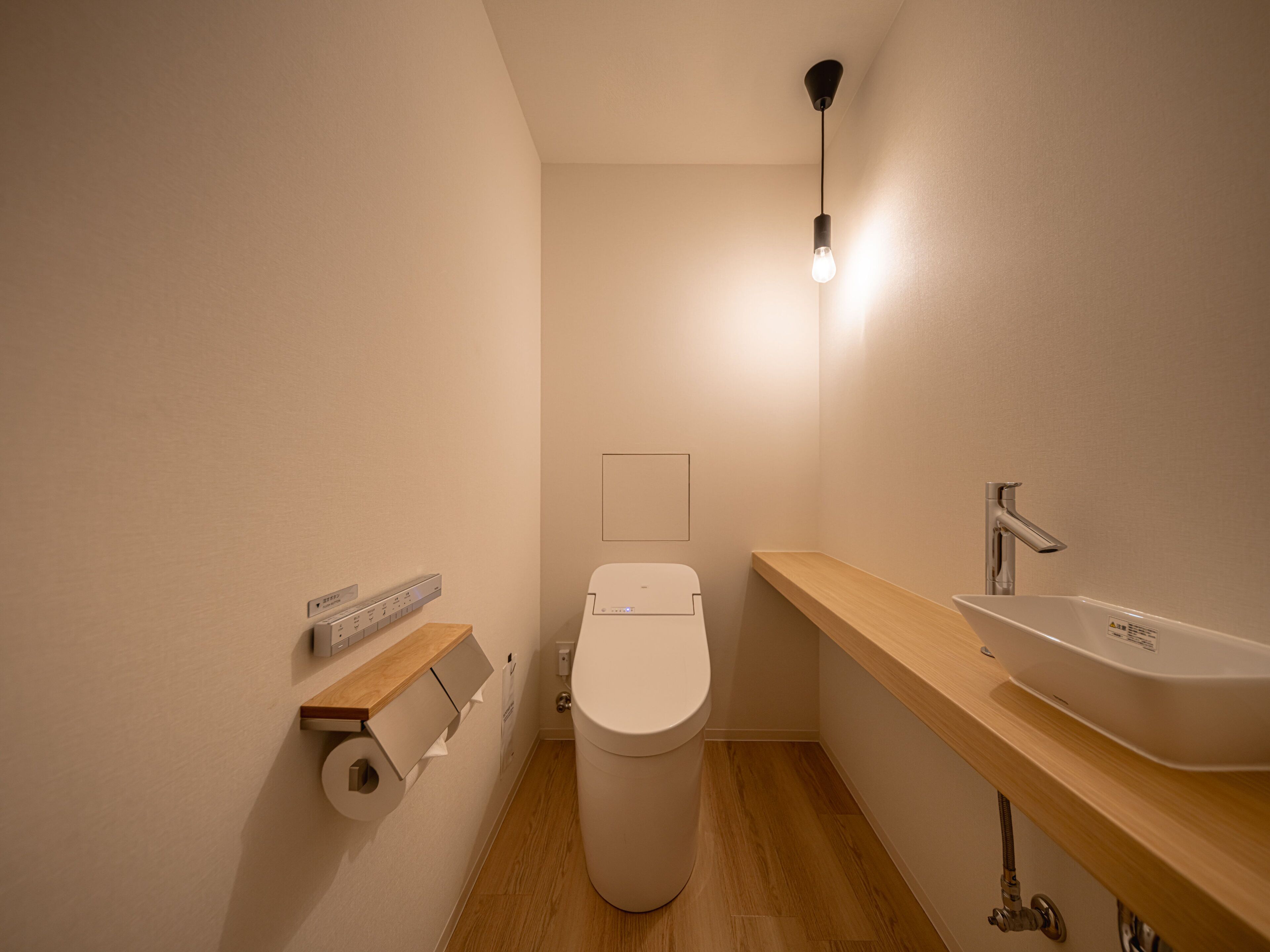 A compact bathroom with a toilet, sink, and a wall-mounted light fixture.