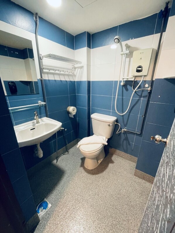 A bathroom with a white sink, toilet, and shower. - De Swift Hotel  (Malacca City)