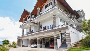Un immeuble résidentiel à plusieurs étages, doté d’une structure de toit remarquable, de nombreux balcons et d’un espace de stationnement couvert.