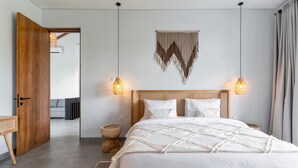 Ein modernes Schlafzimmer mit einem hölzernen Bett, zwei Pendelleuchten, einer gewebten Wanddekoration und einem Holzboden.