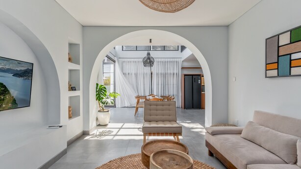Ein modernes Wohnzimmer mit einer Couch, einem Sessel, einem Esstisch und einem großen Fenster.