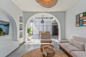 A modern living room with a sofa, a chair, a dining table, and a large window. - Casa Imma Villa by Premier Hospitality Asia (Kerobokan)