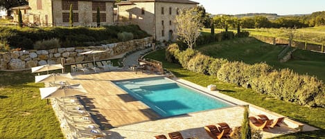 A pool area with lounge chairs and a stone building in the background.