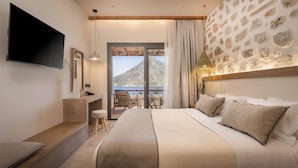 Ein Schlafzimmer mit einem großen Bett, einem Fernseher, einem Schreibtisch und Blick auf die Berge.
