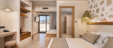 A modern bedroom with a bed, desk, and chair. There is a view of the outdoors through a glass door.