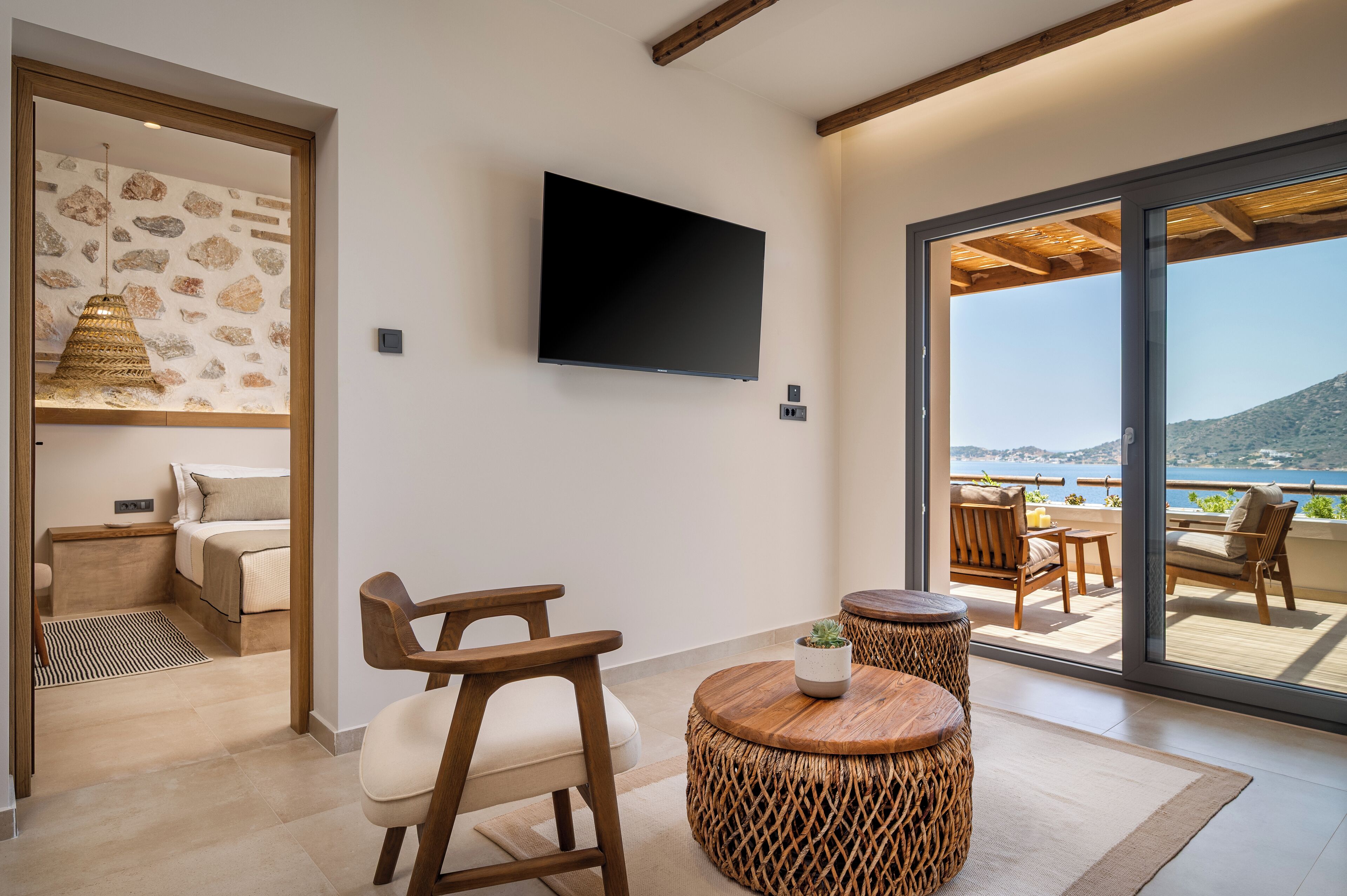 Habitació moderna amb televisió de pantalla plana, mobles de vimetla i vista al mar.