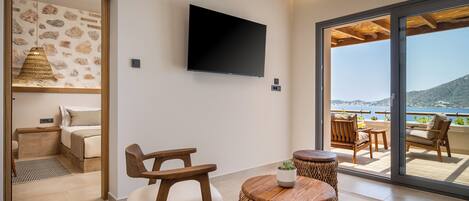 A modern room with a flat-screen TV, wicker furniture, and a view of the sea.