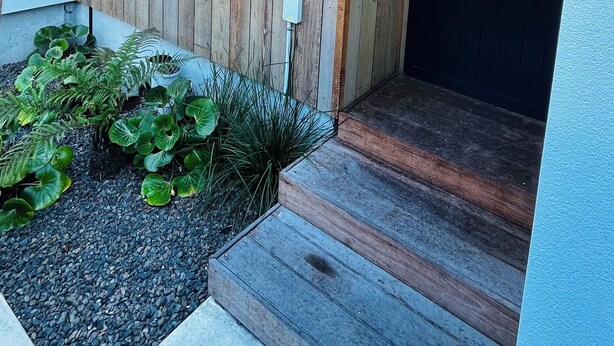 A modern exterior with a wooden panel wall, a black door with the number 3, and a small garden area with plants. - New Merivale townhouse, centrally located by Hagley Park and City. (Christchurch)