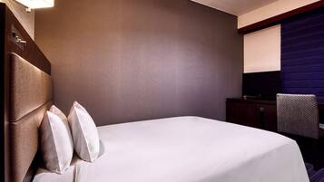 A hotel room with a large bed, a flat-screen TV, a desk, and a chair.
