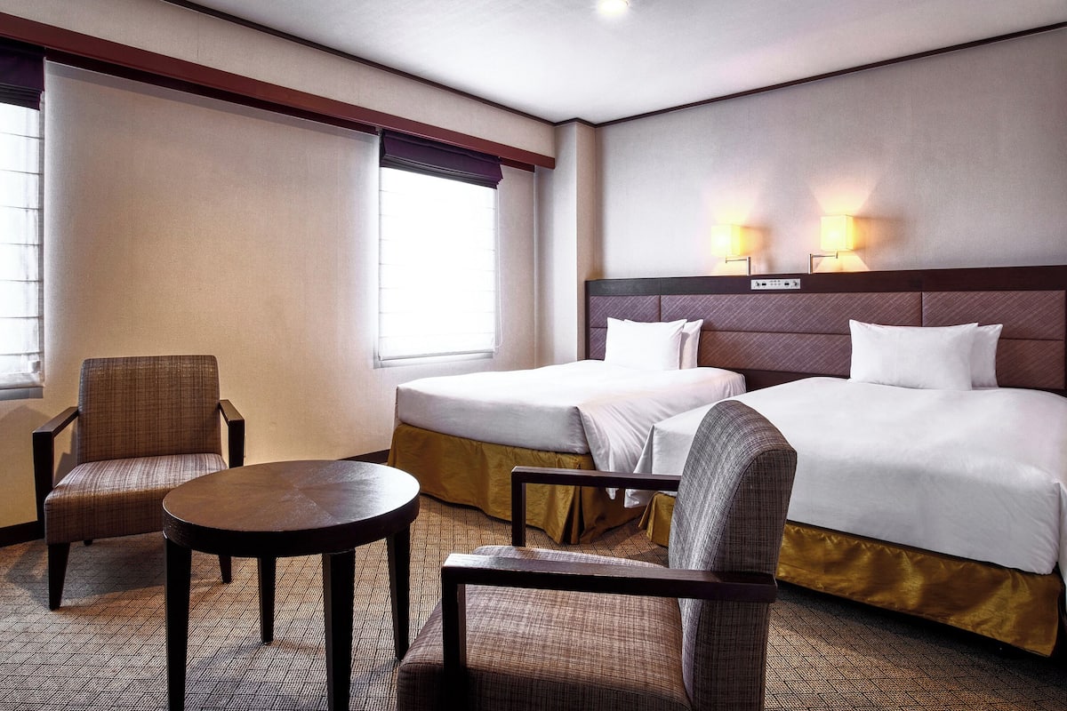 Une chambre d’hôtel avec deux lits, une petite table et deux chaises.