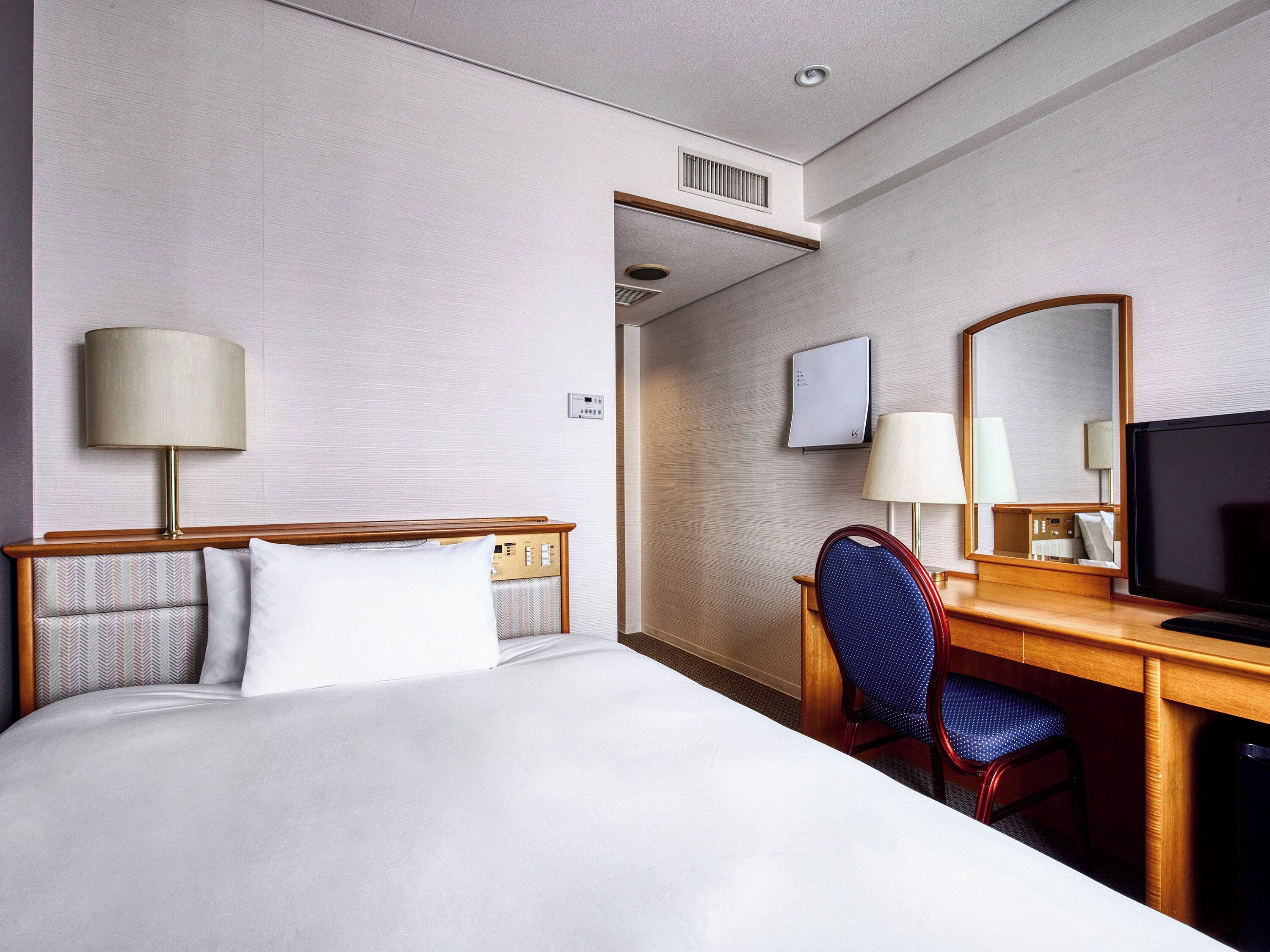Une chambre d’hôtel équipée d’un lit, d’un bureau, d’une chaise et d’un téléviseur.