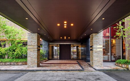 The entrance of the Royal Pines Hotel with a stone facade, a tiled entrance, and a clear view of the interior through the glass doors.
