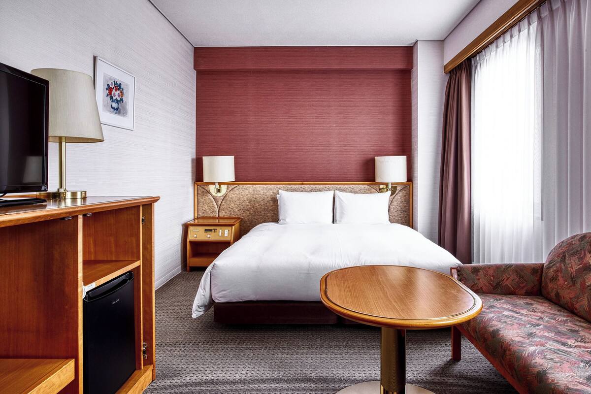 Une chambre d’hôtel équipée d’un lit, d’une télévision, d’un bureau, d’une chaise et d’un canapé.