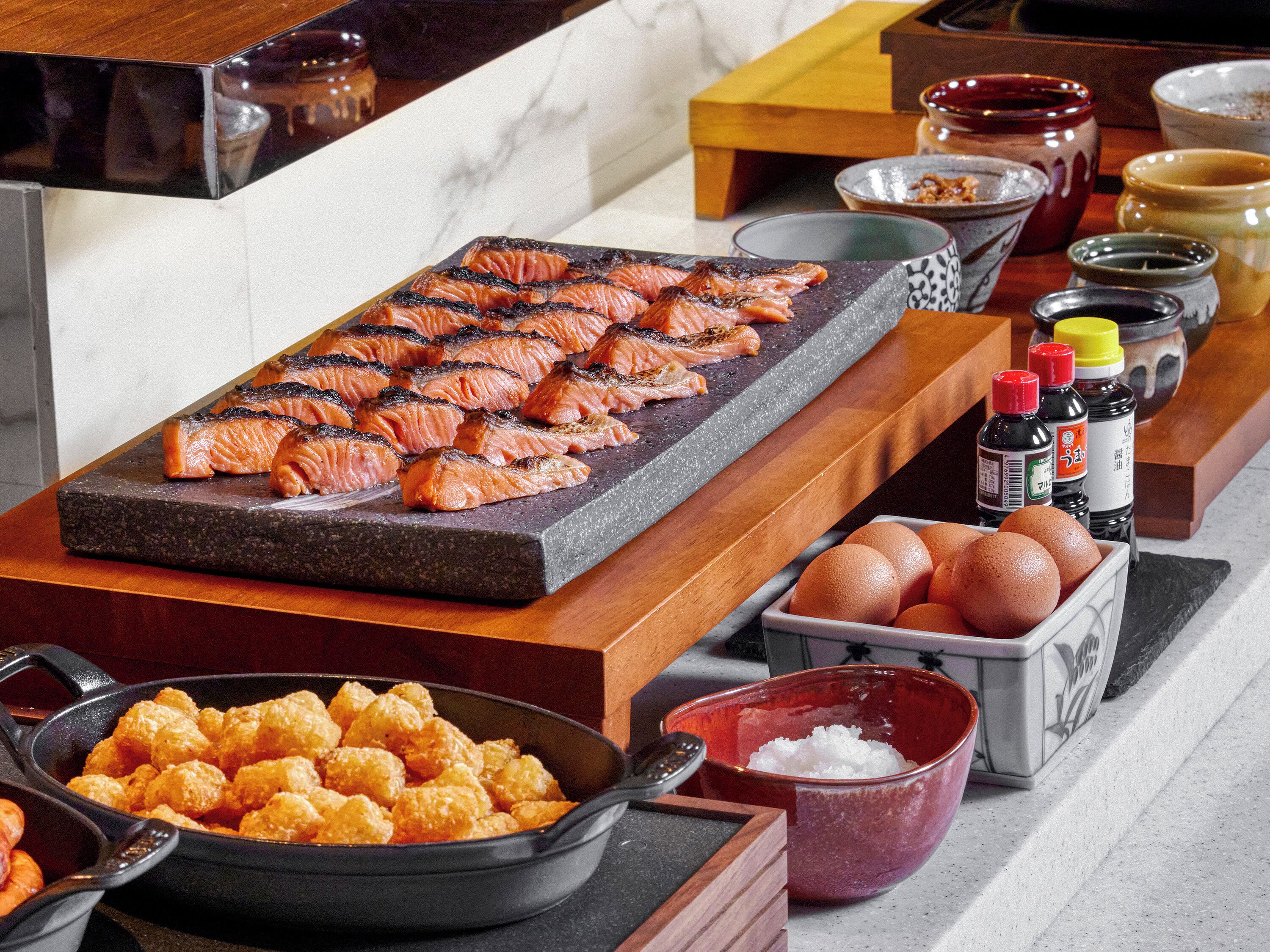 Een buffet met gegrilde zalm, aardappeltjes en sauzen.