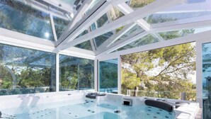 A modern spa with a glass-enclosed hot tub, large windows, and a view of trees. - Villa Ocean View en Portals Nous by Mallorca North Villas (Portals Nous)