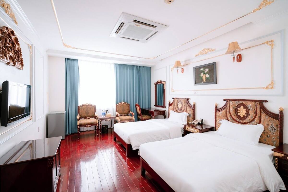 Ein Hotelzimmer mit zwei Betten, einem Fernseher, einem Schreibtisch und einem Stuhl.