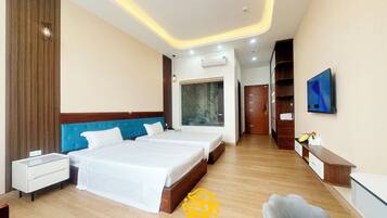 A hotel room with two beds, a desk, a chair, a TV, and a wardrobe.