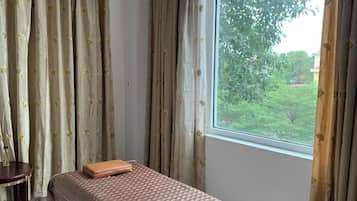 Una habitación con una cama, una mesita y una ventana con cortinas.