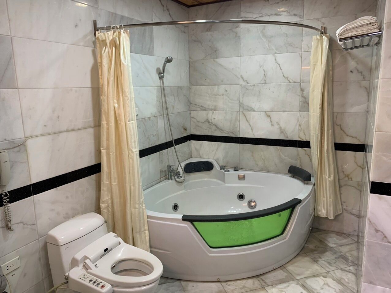A bathroom with a jacuzzi, toilet, and shower curtain.