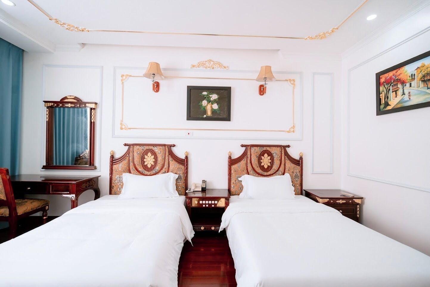 Habitación de hotel con dos camas, un escritorio, una silla, un espejo y un cuadro en la pared.