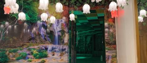 A staircase leading to a room with a mural of a waterfall and greenery.
