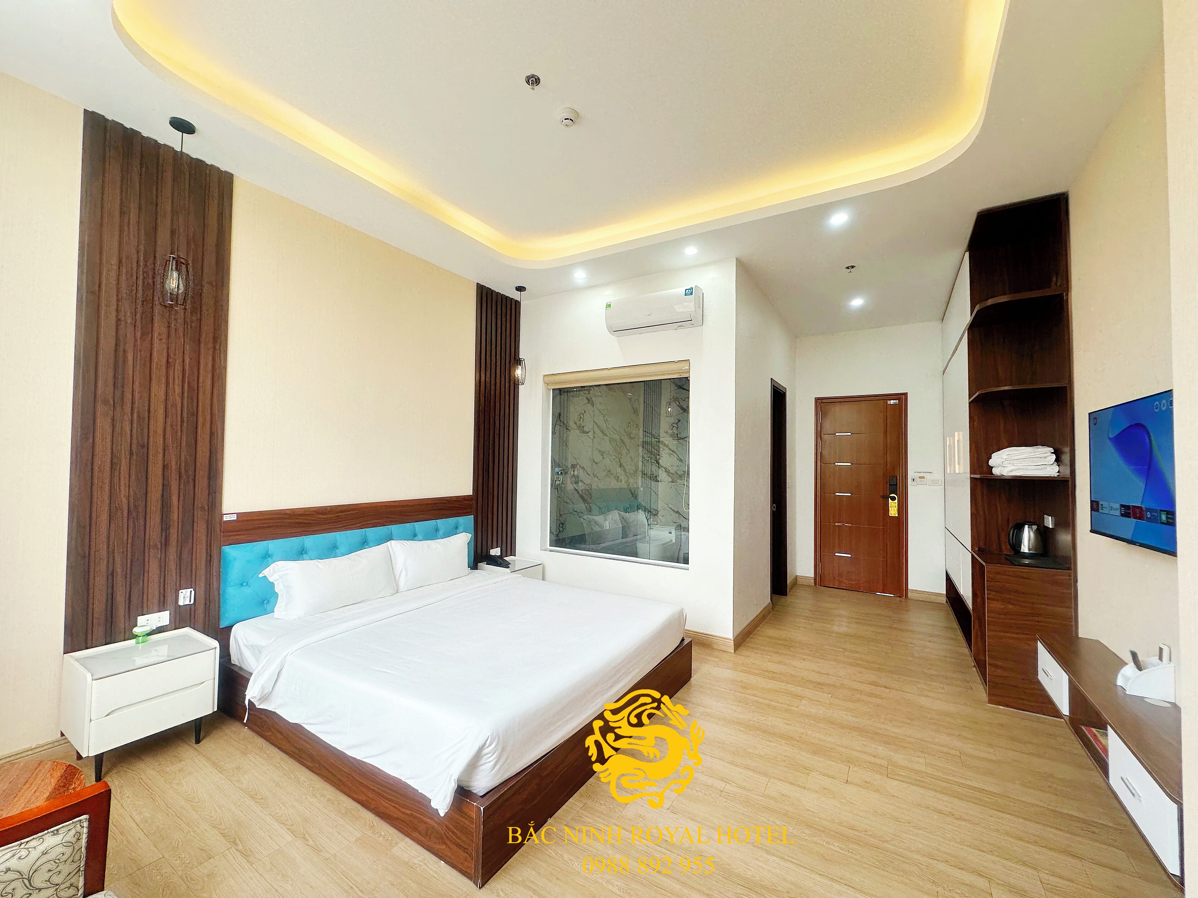 A hotel room with a large bed, a nightstand, a wardrobe, a TV, and a window with a view.
