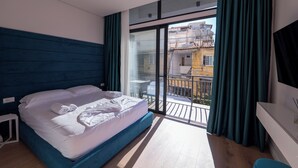 Et moderne hotelværelse med en stor seng, en balkon med udsigt over byen og en skydedør i glas.