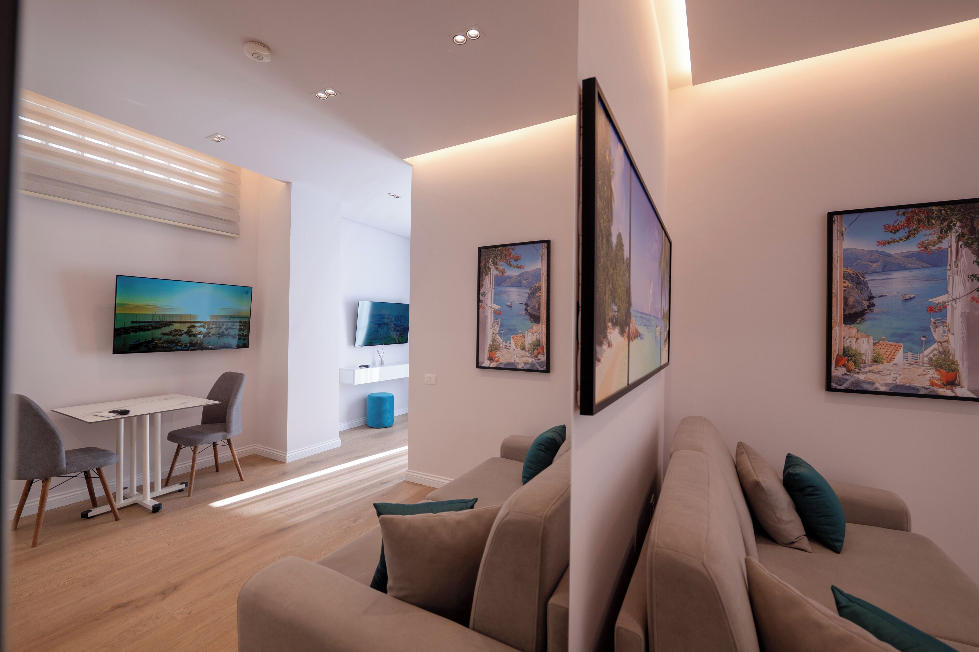 A modern living room with a sofa, a dining table with chairs, and artwork on the walls.
