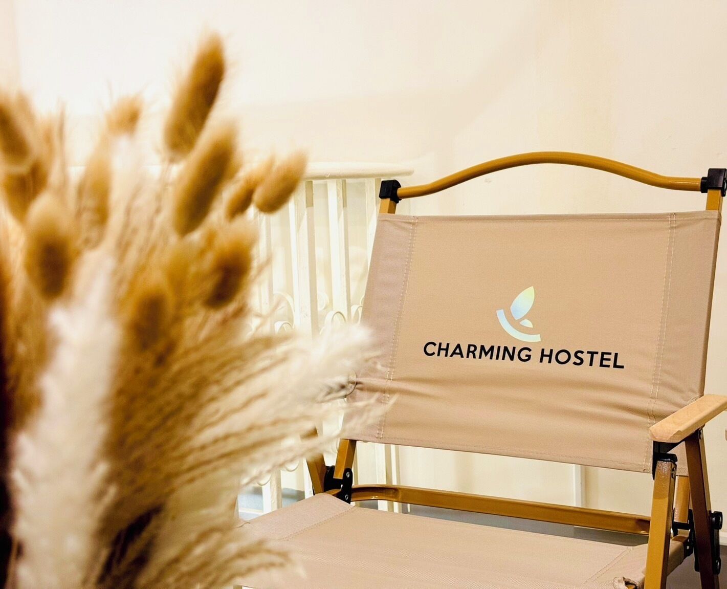 A chair with a beige cushion and a sign that reads "CHARMING HOSTEL" on the backrest.