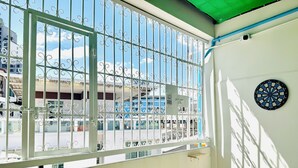 Un balcon avec une grille en métal, un jeu de fléchettes et une petite table.