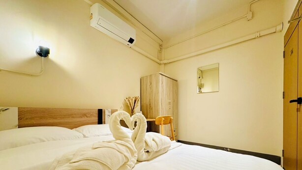 Une chambre d’hôtel comprenant un lit, une tête de lit en bois, une armoire, un miroir et un appareil de climatisation.