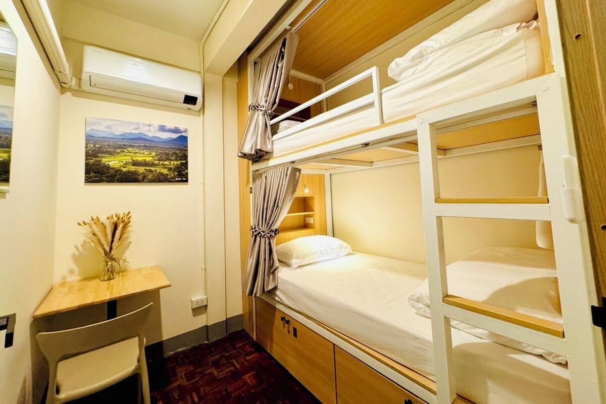 A compact room with bunk beds, a desk, and a small table.
