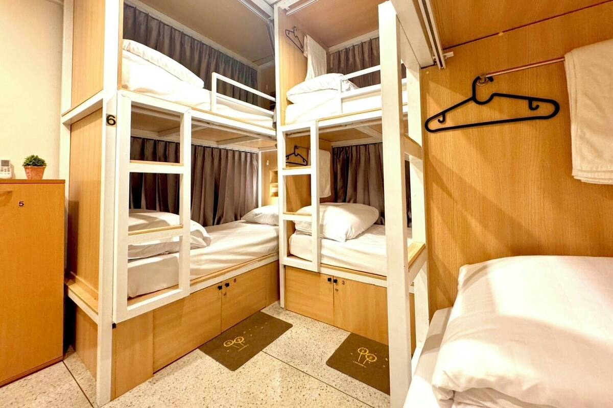 A bunk room with two bunk beds, wooden cabinets, a small plant, and a towel rack.