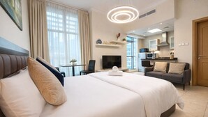 Una habitación de hotel con una cama grande, un sofá, un televisor, una kitchenette y un comedor.