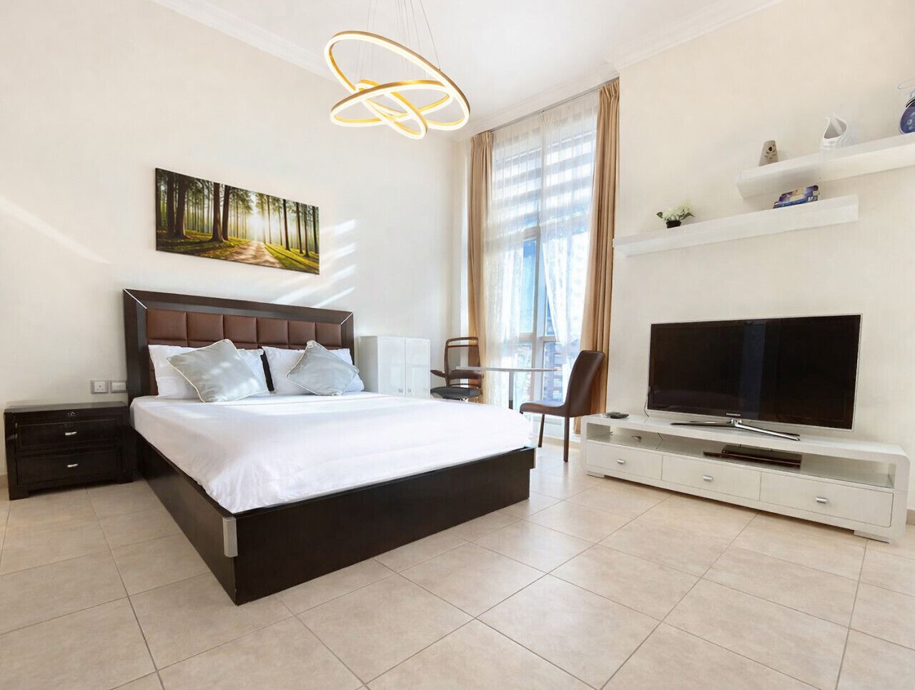 A modern hotel bedroom with a large bed, a TV, and a painting on the wall.