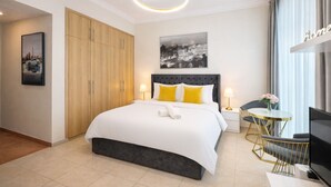 Une chambre d’hôtel comprenant un lit, une télévision, un bureau avec une chaise, une armoire et un tableau au mur.