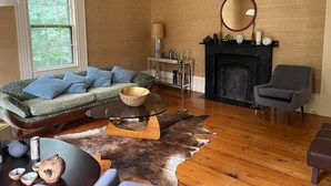 Ein Wohnzimmer mit Sofa, Kamin, Spiegel und Couchtisch.