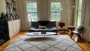 Ein Wohnzimmer mit Sofa, Couchtisch, Bücherregal und Kamin.