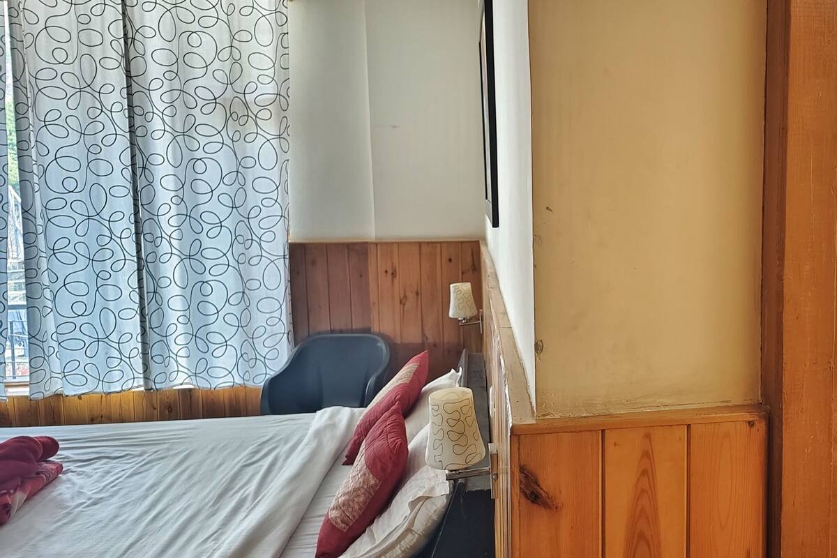 A room with two beds, wooden walls, and a small table.