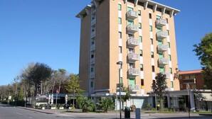 Ein mehrgeschossiges Hotel mit Balkonen, einem wolkenlosen Himmel und einer Straße mit abgestellten Fahrrädern.