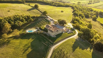 Una vasta tenuta con piscina, diversi edifici e ampi campi verdi.