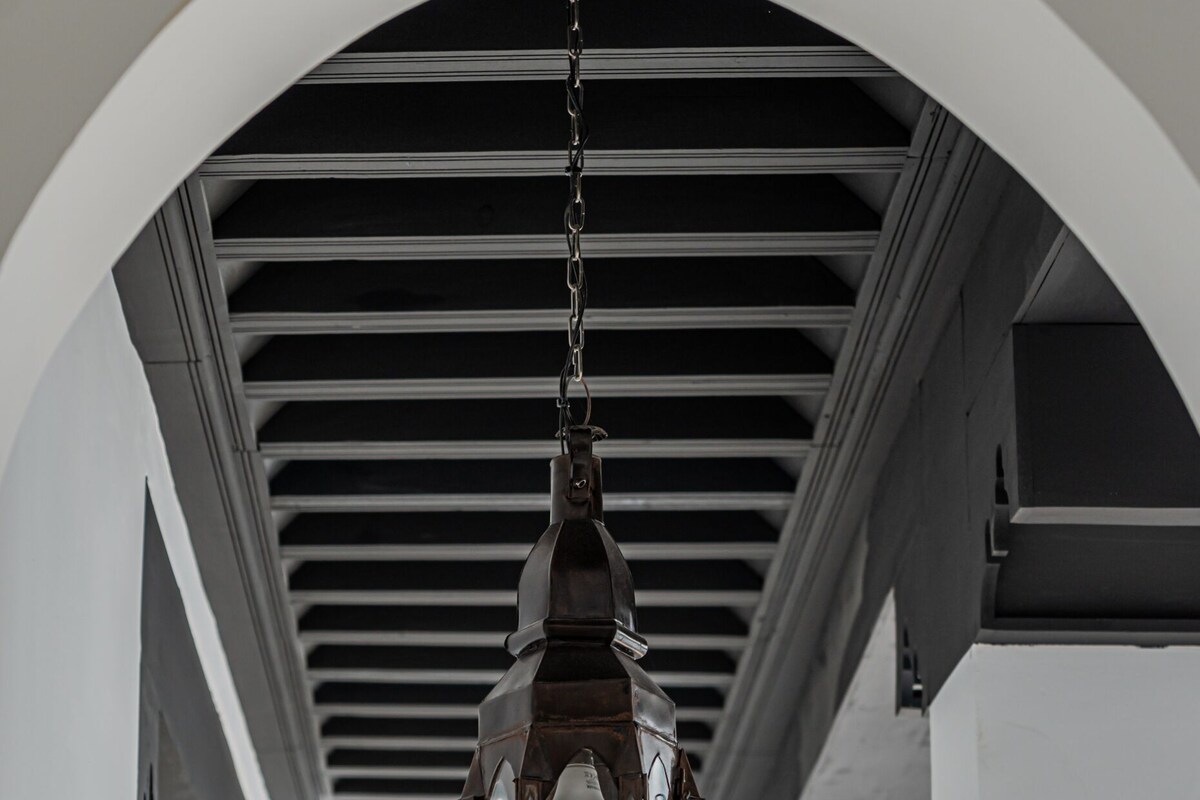 A hanging lantern in a hallway with white columns and a black ceiling.